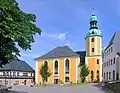 Kostel sv. Bartoloměje s roubeným měšťanským domem vlevo
