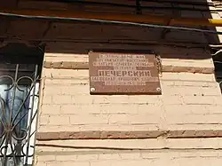 Malá hnědá pamětní deska visící na zdi domu v Rostově na Donu, kde žil Pečerskij.