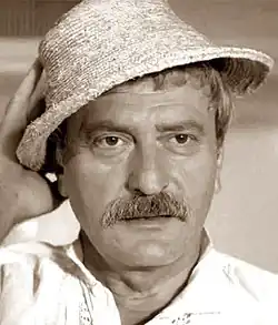 Fotografie Amzy Pelley z filmu ve chvíli, kdy se jako postava strýčka Mărina dívá z hotelového pokoje na moře.