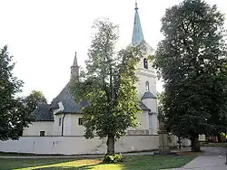 Kostel svatého Jakuba Staršího s obrannou ohradní zdí se střílnami, před ním barokní socha svatého Jana Nepomuckého