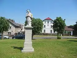 Socha Jana Nepomuckého na upravené návsi, vzadu dům č. p. 2