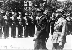 Dva muži v uniformách hledí na nastoupenou jednotku
