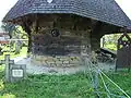 Detail polygonálního závěru s kulatým oknem, přesahující střechou a kamenným soklem