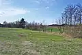 Potok po opuštění lesa, lemován stromy a keři