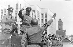 Generál von dem Bach-Zelewski přijímá hlášení při příjezdu na Leninovo náměstí v Minsku. Ve voze za ním stojí SS-Gruppenführer Kurt von Gottberg.
