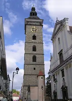 Pohled na Černou věž od náměstí Přemysla Otakara II. Před ní je vidět pomník Jana Valeriána Jirsíka a vpravo průčelí katedrály sv. Mikuláše. Za věží dále pokračuje ulice U Černé věže