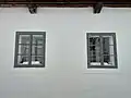 Detail oken do světnice s plechovými závěsy