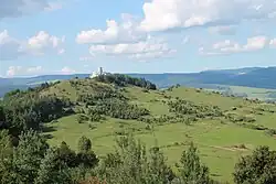 Suché louky, v pozadí hřebeny hor, věž Spišského hradu