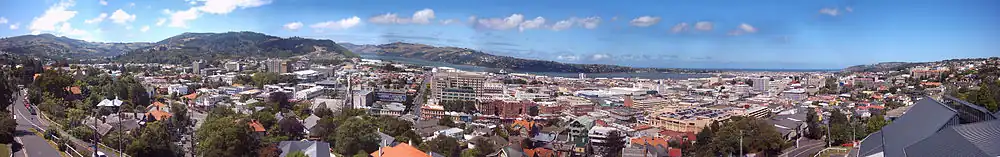 Pohled 180° na Dunedin z kopce na západě; Mount Cargill je zcela vlevo; poloostrov Otago Peninsula je v pravé části, vzadu