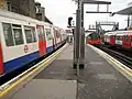 Vlevo vlak linky Metropolitan line směřující na sever do stanice Wembley Park, vpravo odjíždějící vlak linky Jubilee line směřující na sever do stanice West Hampstead, úplně vpravo stojí ve stanici vlak linky Jubilee line směřující na jih do stanice Swiss Cottage