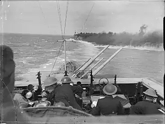 Pohled z můstku protiletadlového křižníku HMS Euryalus během druhé bitvy u Syrty. Sesterská HMS Cleopatra pokládá kouřovou clonu, aby zakryla konvoj před Italy