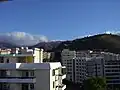 Pohled z 11. patra hotelu Duas Torres na Avenida Monumental na sever. V popředí na pravé straně Pico da Cruz. V dálce na pozadí hor bílý kostel sv. Martina.