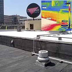 Na termosnímku (v pravém horním rohu) je porovnání teploty na povrchu černé asfaltové střechy (v dolní části snímku) s bílou střešní krytinou z elastomeru (v prostřední části snímku).