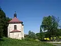 Pohled od jihovýchodu na kostel a přilehlý hřbitov. V pozadí zřícenina hradu Košumberk