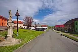 Náves s křížem a památkově chráněnou zvoničkou