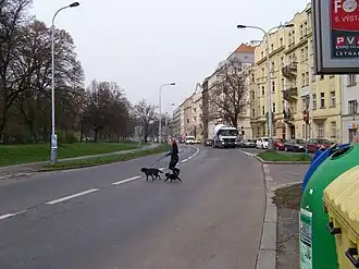 za stromem domy 7/1, 164/2 v Mahenově ulici a 15/1 v Brožíkově ulici z pohledu od ulice Vrchlického v Praze