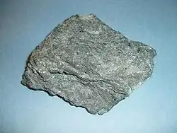 Komatiit z pásma Abitibi v kanadské provincii Ontario. Vzorek je asi 9 cm velký. Viditelné jsou krystaly olivínu, spinifexová struktura není přítomna