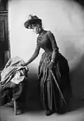 Žena Severina Nilsona Rosalie Platzman-Eberstein, elegantně oblečená ve fotografickém studiu, slouží jako model pro obraz, kde bude pozadí nahrazeno přírodou se stromy a horami, asi 1875-1900