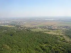 Jenčice (vpravo uprostřed až k lesu vlevo uprostřed) pohledem z vrchu Košťálu