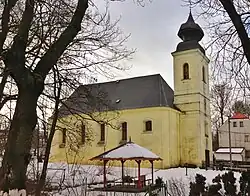 Žlutý kostel s černou střechou a věží