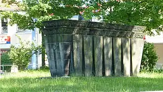 Barevná fotografie s pohledem na mohutný kamenný náhrobek ve tvaru tumby