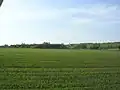 Pohled na Krteň od Řeporyj, zcela vpravo Chaby. K zástavbě je určena prvořadě plocha vpravo v pozadí.