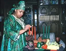 Žena zapalující svíčky kinara na stole ozdobeném symboly svátku.