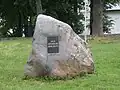 Kámen s pamětní deskou první zmínky farního kostela v Lüganuse