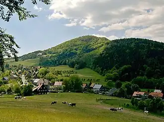 Barevná fotografie s pohledem na dva zalesněné horské hřebeny