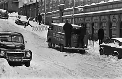 Meritullinkatu 25. Dva muži stojící za dodávkou na zasněženém Meritullinkatu. Pohled z Liisankatu směrem na Kruununhaankatu, asi 1970