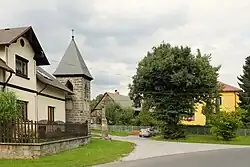 Náves se zvonicí a krucifixem