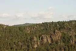 Pohled na Jonsdorfské skalní město z nedalekého pískovcového masívu Nonnenfelsen. V pozadí rozhledna na Hvozdu