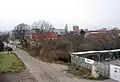 Statek č. o. 47 (č. p. 1213) obklopený novou zástavbou a skladem, v pozadí ostatní původní domky