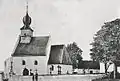 Černobílá fotografie kostela asi z roku 1916, okolí kostela je beze stromů, v popředí stojí dvě postavy
