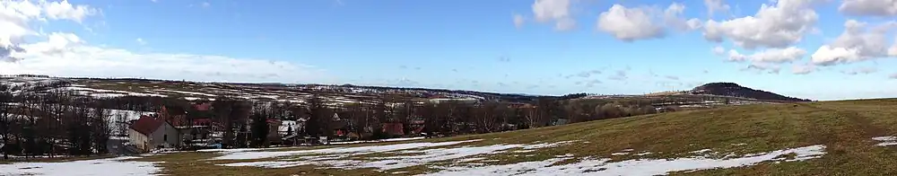 Pohled na část Krásného Lesa a vrch Špičák (vpravo), který je se 723 m n. m. druhým nejvyšším bodem katastrálního území. Pod Špičákem je vidět část dálnice D8.