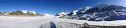Panorama zamrzlého jezera Petrova v masivu Ak-Šijrak. Na panoramatické fotografii je vidět zamrzlé a zasněžené jezero Petrova, do něj vtékající ledovec Petrova, a zasněžené vrcholy masivu AkŠijrak v pozadí.