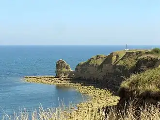 Současný pohled na útes Pointe du Hoc s památníkem vpravo nahoře.