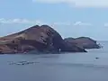 Zátoka Baía de Abra. Na hladině jsou zařízení oceánografického výzkumu. Malá špička zcela vzadu (v pravé polovině snímku) je maják.