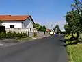 Silnice procházející Chomutovicemi se zastávkou autobusu PID