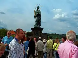 Turisté u sochy svatého Jana Nepomuckého na Karlově mostě