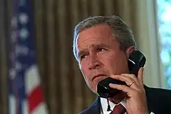 Prezident W. Bush mluví telefonicky s newyorským guvernérem Georgem Patakim a starostou New Yorku Rudym Giulianim, dva dny po útocích z 11. září. (Draper, 2001)