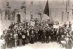 černobílý pohled na shromáždění asi 100 osob, vesměs mužů