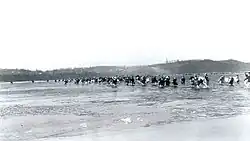 Lidé brodí řeku, ve které jsou vidět kusy ledu, 3. prosince 1950