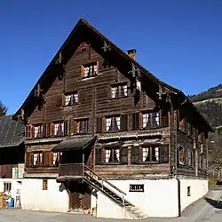 Rheintalhof ve Schnifis. Nad dveřmi do sklepa se nachází dřevěné schodiště do krytého vchodu