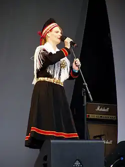 Stojící zpívající žena v šatech zdobených tradičními barvami