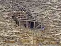 Prohlubeň do pyramidy kolem které se nachází dřevěné lešení. Vedou k ní po stěně pyramidy nepravidelné kamenné schody s kovovým zábradlím