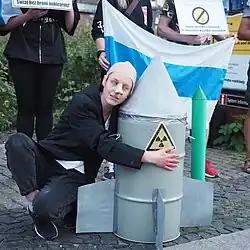 Rusové během protestu v polské Vratislavi 8. srpna 2022 proti invazi na Ukrajinu. (V pozadí bílo-modro-bílá vlajka; v popředí protestující karikující Putina s jadernou střelou)
