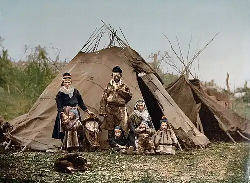 Fotografie rodiny o 8 lidech stojících a klečících před svými stany