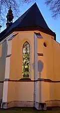 Východní strana kostela s vitrážovým oknem z 19. století; původně byl kolem kostela zřízen hřbitov, dnes je v areálu děkanství provedena parková úprava