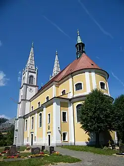 Pohled na jižní stěnu kostela a jeho závěr, věže jsou v pozadí, okolo kostela se nacházejí náhrobky
